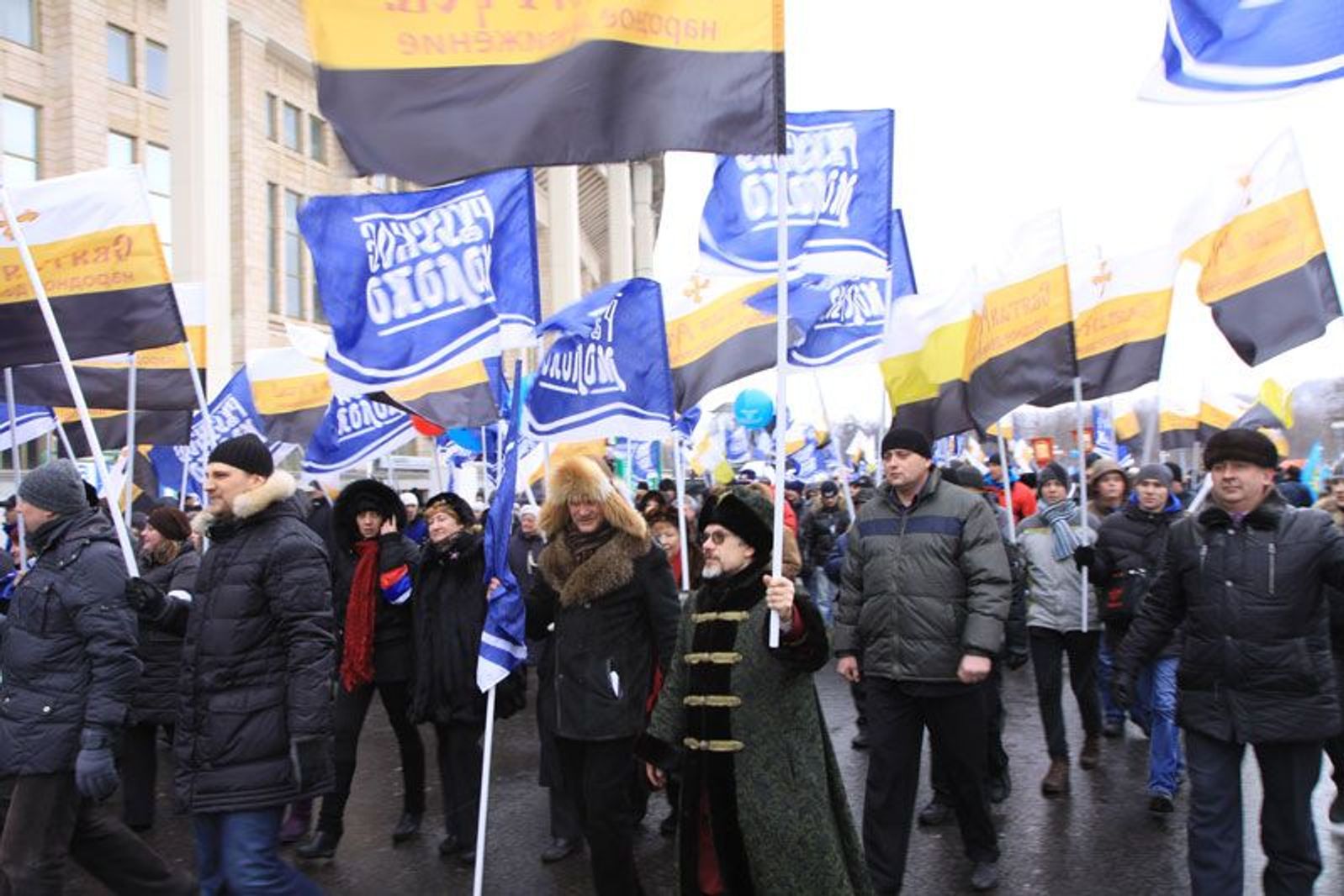 A procession carrying flags bearing the logos of the Russkoe Moloko company at a rally in support of Vladimir Putin at Moscow’s Luzhiki Stadium in 2012. 